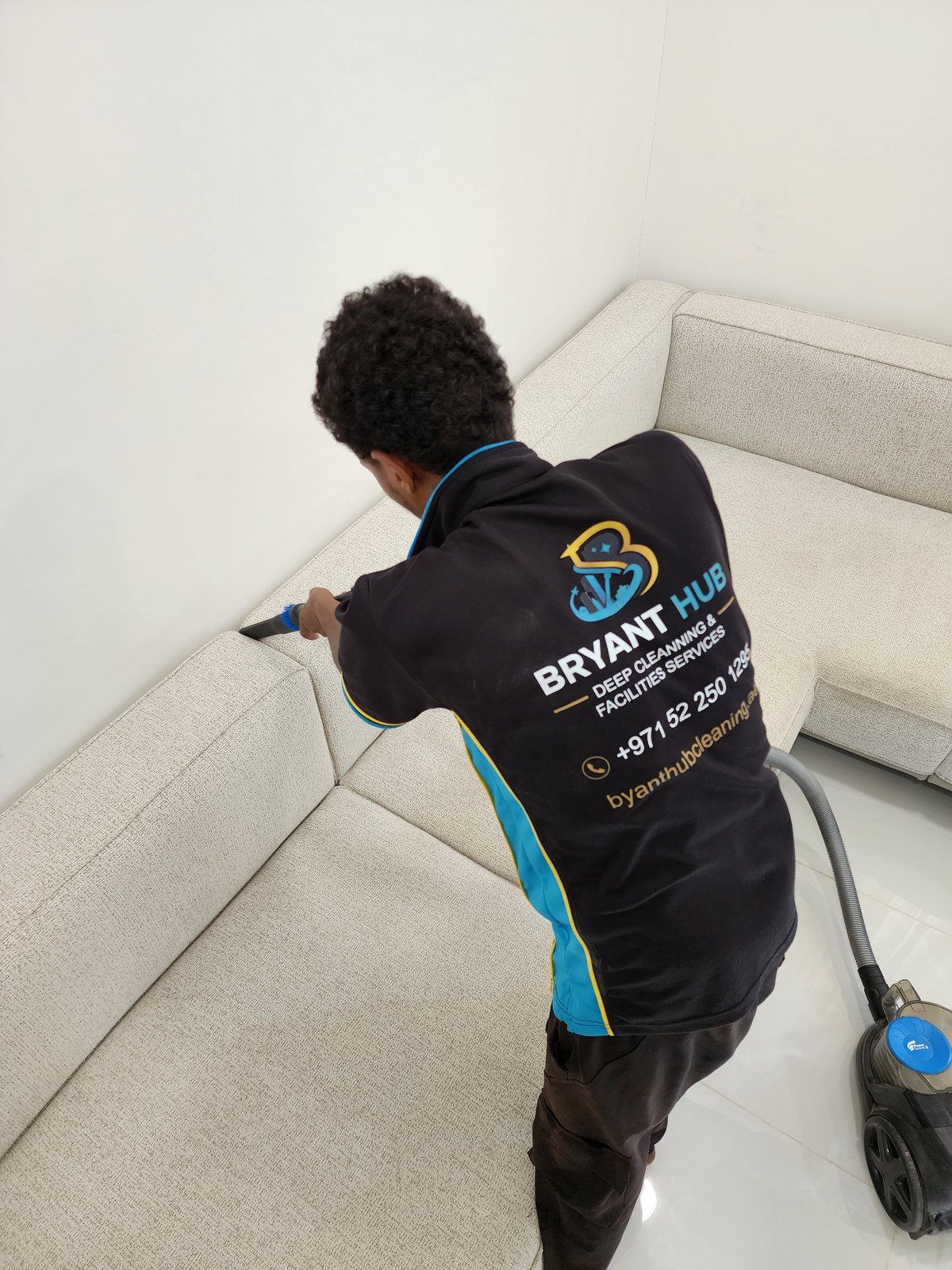 Bryant Hub Cleaning sofa cleaning Al Ain, uniformed technician vacuuming a sofa before extraction